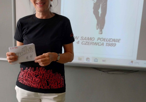Nauczycielka z ulotką na tle plakatu wyborczego z 1989 roku