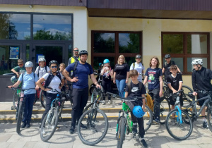Uczniowie wraz z nauczycielami podczas przygotowania do rajdu rowerowego przed budynkiem szkoły.