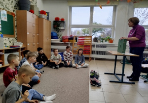 Uczniowie siedzą na dywanie