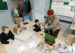 Uczniowie wraz z nauczycielem wieszają karmnik zrobiony z odpadów.