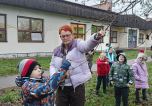 Uczniowie wraz z nauczycielem wieszają karmnik zrobiony z odpadów.