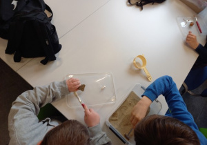 Uczniowie w trakcie eksploracji łopatką i czyszczenia pędzlem zabytku