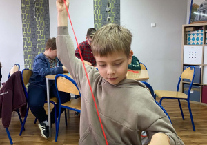Uczniowie siedząna krzesłach przy stolikach na zajęciach z rzemiosła