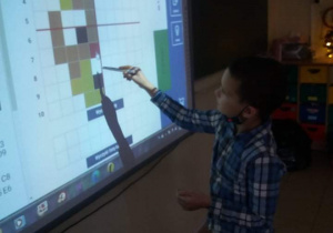 Dziecko rozkodowuje obrazek na tablicy interaktywnej.