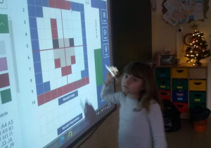 Dziecko rozkodowuje obrazek na tablicy interaktywnej.