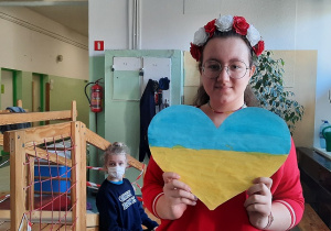 Uczennica trzyma w ręku serce w barwach Ukrainy