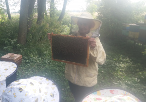 Pani pszczelarz pokazuje uczniom pszczoły i królową z bliska