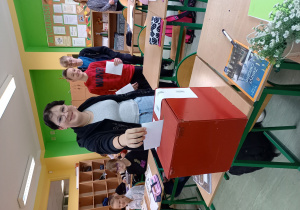 Uczeń wrzucający kartę wyborczą do urny - klasa VIII a