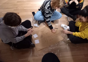 Warsztaty - grupa dziewcząt z 7b siedzi i pisze na kartonach- planuję założenie firmy