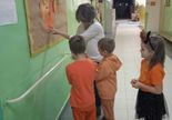 Dzieci wraz z nauczycielką przyczepiają swoje prace na tablicy.