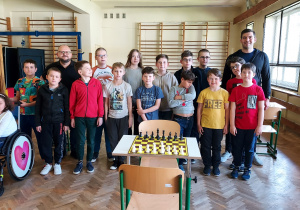 Uczniowie i nauczyciele na sali gimnastycznej turniej szachów