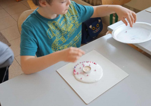 Uczeń ozdabia swój świecznik z masy porcelanowej.
