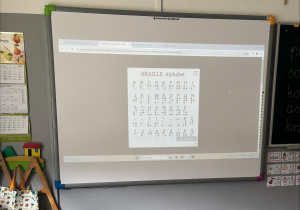 Tablica multimedialna z wyświetlonym alfabetem Braille'a.